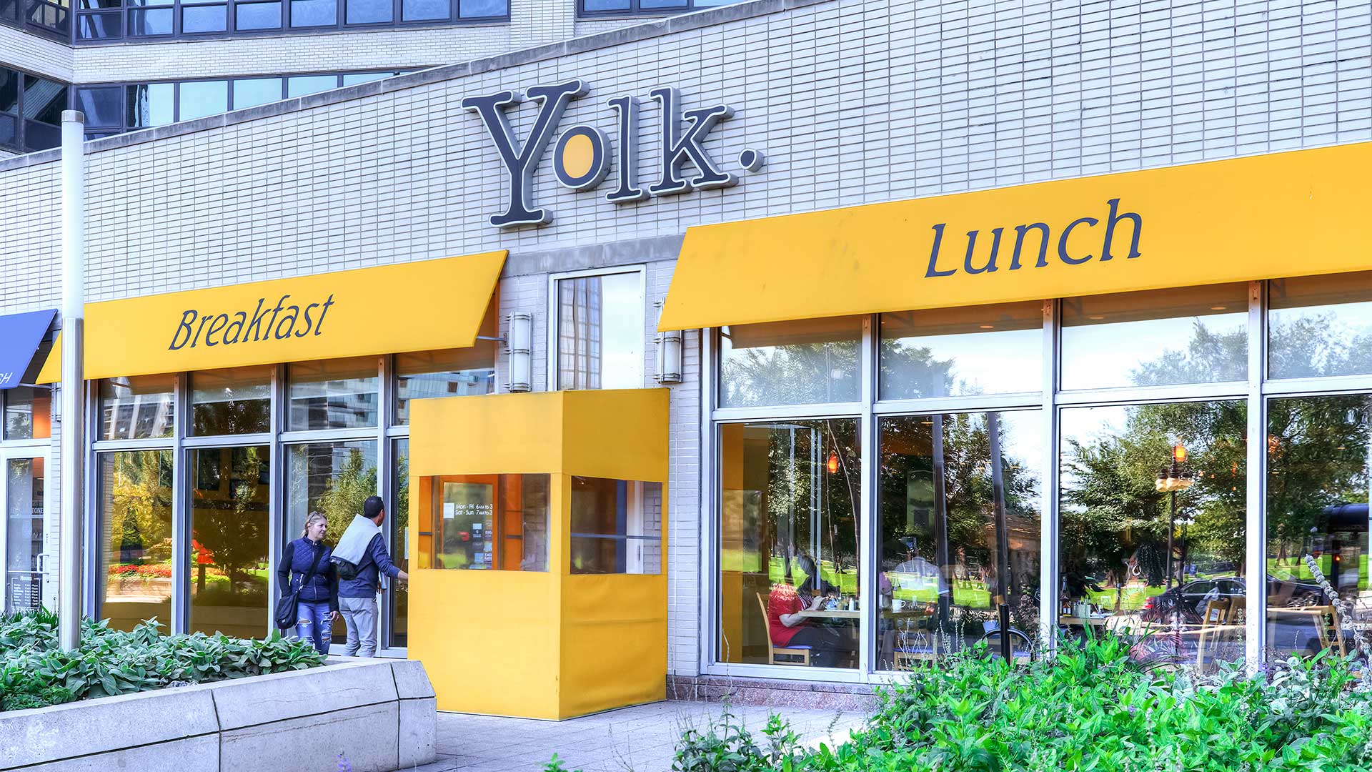 The storefront of Yolk restaurant located at Eleven Thirty. Yellow awnings hang over the windows.